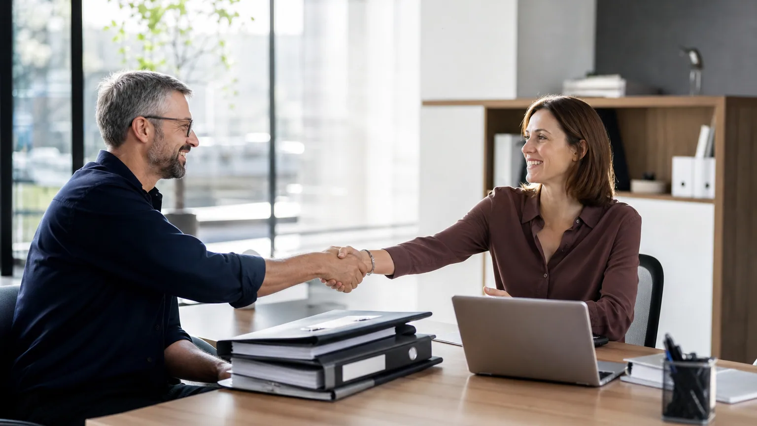 Dirigeant de TPE remettant ses classeurs comptables à un nouvel expert-comptable dans son cabinet